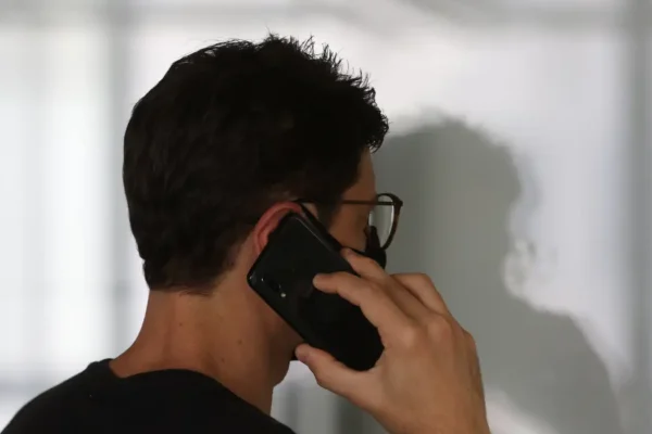 Pessoa segurando um telefone celular em uso. Foto: Tânia Rêgo/Agência Brasil